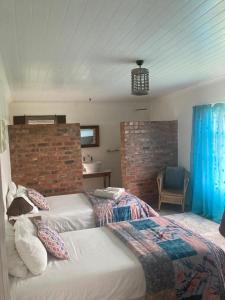 a bedroom with two beds and a brick wall at Ou Werf Farm Cottage in Bredasdorp
