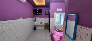 a bathroom with purple walls and a sink and a mirror at Villa Dono in Pasuruan