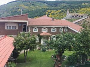 a large brown house with trees in front of a mountain at Casa Hostal Olga - Castilla y León in Cofiñal