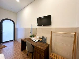a room with a desk and a television on a wall at VÂN TRANG GARDEN HOTEL 2 in Vĩnh Long