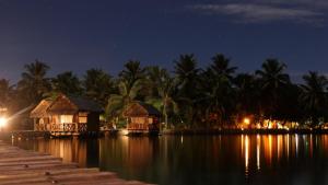 a couple of houses on a body of water at night at Lakana Hotel in Sainte Marie