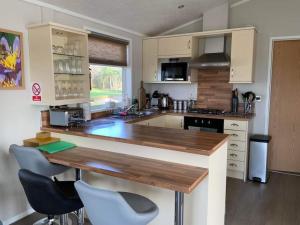 a kitchen with a wooden counter top and chairs at Honeybee Lodge in Wisbech