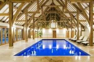 a large swimming pool in a building with wooden ceilings at Honeybee Lodge in Wisbech