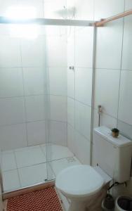 y baño blanco con aseo y ducha. en Casa Arembepe en Camaçari