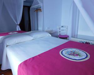 a white bed with a pink blanket and a plate on it at Casa de la Abuela Pepa in Zafarraya