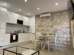 a kitchen with a table and chairs and a stone wall at Cloe Apartment in Split