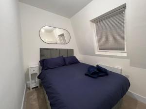a bedroom with a blue bed and a mirror at Star London Finchley Lane 3-Bed Retreat in Hendon