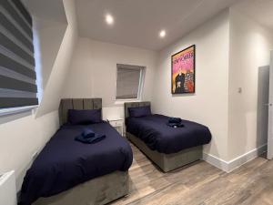 a bedroom with two beds with blue pillows in it at Star London Finchley Lane 3-Bed Retreat in Hendon