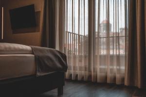 Schlafzimmer mit einem Bett und einem Fenster mit Vorhängen in der Unterkunft Mediterraneo Luxury Room Esztergom in Esztergom
