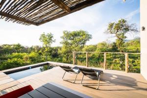 een terras met 2 stoelen en een zwembad bij Kruger Cliffs Lodge in Hoedspruit