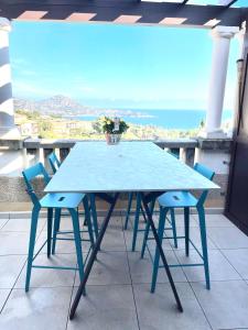 Village Cap Esterel duplex vue mer centre في أغاي - سان رافائيل: طاولة زرقاء وكراسي على شرفة مع المحيط