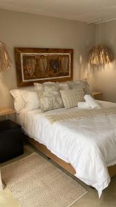 una camera da letto con un grande letto con lenzuola e cuscini bianchi di Luxury Upmarket Guesthouse 20 on 4th a Rustenburg