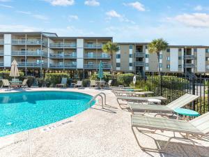 a swimming pool with lounge chairs and a building at Lighthouse Point 4B in Tybee Island