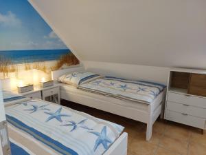 2 Betten in einem Schlafzimmer mit Blick auf den Strand in der Unterkunft Trekvogels Utkiek in Dornum