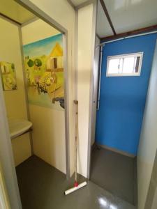 een kleine badkamer met een blauwe deur en een spiegel bij Uniek overnachten in de prehistorie in Lelystad