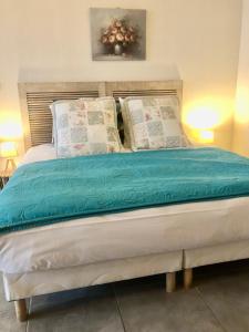 Schlafzimmer mit einem Bett mit blauer Bettwäsche und Kissen in der Unterkunft Maison d'hôtes Aux Deux Cigognes in Gries