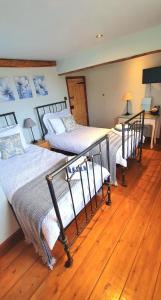 two beds in a room with wooden floors at Well Cottage Country Accommodation in Brockley Green