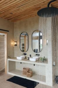 a bathroom with two sinks and two mirrors at Gwahumbe Game & Spa in Mid Illovo