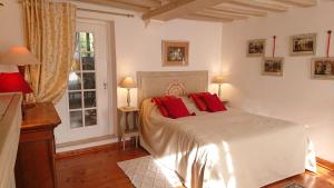 1 dormitorio con 1 cama blanca grande con almohadas rojas en A l'Ombre du Tilleul en Giverny