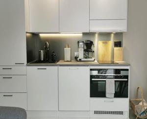 a kitchen with white cabinets and a microwave at Apartment Beach & Golf Kalajoki in Kalajoki