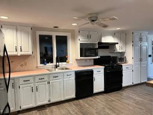 a white kitchen with white cabinets and black appliances at A charm Cape house centrally located close to everything that Cape code offers in Yarmouth
