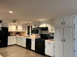 a kitchen with white cabinets and black appliances at A charm Cape house centrally located close to everything that Cape code offers in Yarmouth