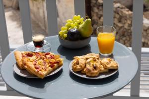 un tavolo con due piatti di pizza e un bicchiere di succo d'arancia di Azure Kimolos a Kimolos