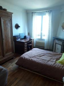 a bedroom with a bed and a desk with a laptop at Vue sur les toits de Paris, tour Effeil, centre malakoff, chambre chez l'habitant, sans ascenseur, à deux pas de Paris in Malakoff