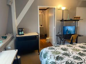 a bedroom with a bed and a desk with a television at Chambre Archi in Écourt-Saint-Quentin