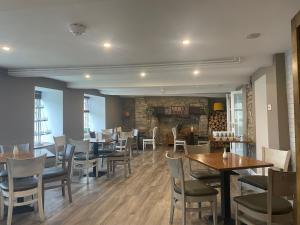 a restaurant with tables and chairs and a fireplace at Northover Manor Hotel in Ilchester