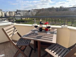 einen Holztisch mit zwei Gläsern Wein auf dem Balkon in der Unterkunft Issy - les jardins du séminaire in Issy-les-Moulineaux