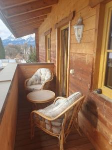 a porch of a cabin with two chairs and a table at Ski apartment St. Johann in Tirol, Kitzbuheler Alpen in Sankt Johann in Tirol