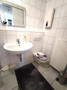 La salle de bains blanche est pourvue d'un lavabo et de toilettes. dans l'établissement Klein aber fein 2, à Düren