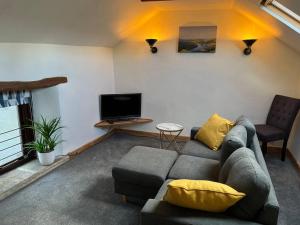 sala de estar con sofá y TV en The Barn Behind en Castleton