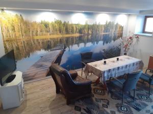 ein Esszimmer mit einem Tisch und einem Gemälde eines Sees in der Unterkunft Zacisze nad Rospudą in Filipów