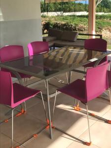a glass table with pink chairs around it at villa domaine des palétuviers in Le Moule