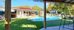 a backyard with a swimming pool and a house at La Rose du Bresil Marie-Galante in Capesterre