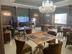 ein Esszimmer mit Tischen und Stühlen und einem Kronleuchter in der Unterkunft Lion Hotel in Astana