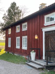 a red house with a wooden door and a porch at Hova Prästgård Bed & Breakfast in Hova