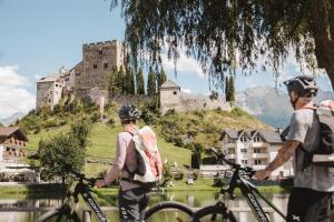- un groupe de personnes debout avec des vélos devant un château dans l'établissement Alpine Resort Goies Superior, à Ladis