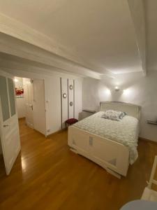 a bedroom with a white bed and a wooden floor at Domaine de la Provençale in Saint-Didier-de-la-Tour