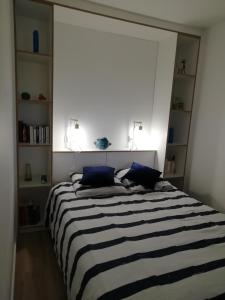 um quarto com uma cama listrada em preto e branco com almofadas azuis em Vue Belle île em Quiberon