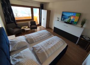 a bedroom with two beds and a flat screen tv at Pension zum Mühlrad in Millstatt