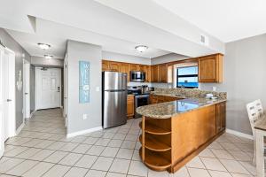 a kitchen with wooden cabinets and a stainless steel refrigerator at Spacious Seaside Beach and Racquet 3706 with Pool and Comfort Amenities in Orange Beach