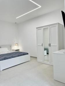 Dormitorio blanco con cama y armario de cristal en Seashell Guest House, en Torre Marino