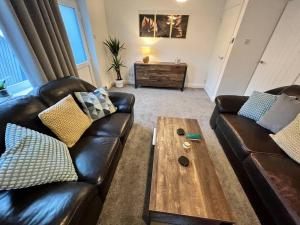 a living room with two leather couches and a coffee table at Very comfy 3 bed town house in Ashton under Lyne