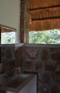 a bathroom with a sink and a stone wall at Rutete Eco Lodge in Rwinkwavu