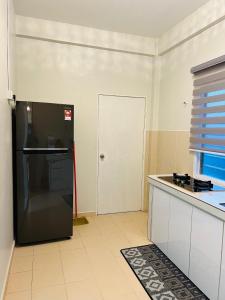 eine Küche mit einem schwarzen Kühlschrank und einer Tür in der Unterkunft KakJie & AbgDin Homestay in Kampong Kemaman
