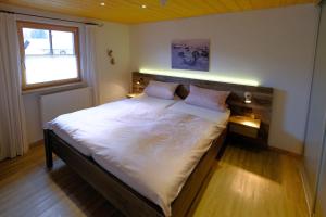 um quarto com uma cama grande com lençóis brancos e uma janela em Ferienwohnung Mitteldorf em Oberammergau
