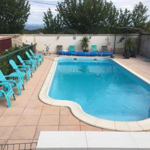 - une piscine avec des chaises bleues à côté d'un bâtiment dans l'établissement Le Clos des Gites, maisons de vacances,, à Châteauneuf-Val-Saint-Donat